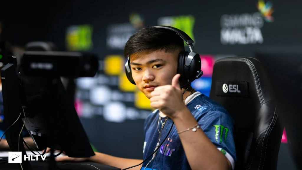 Jogador profissional de Counter-Strike da equipe MIBR durante competição da ESL, usando headset gamer e fazendo sinal de positivo em frente ao computador em palco de eSports.